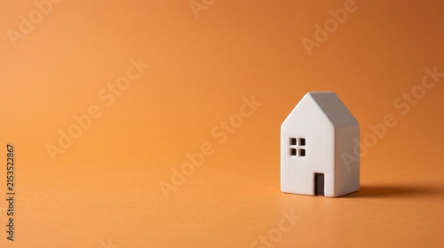 Tiny White House Model on Warm Orange Background with Large Left Copy Space for Real Estate, Mortgage, Property Investment and Home Ownership Concept