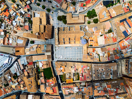 An aerial drone surveys the town square and terracotta tiled roofs in Lorca, Spain. European urban architecture, historic town and travel destination
