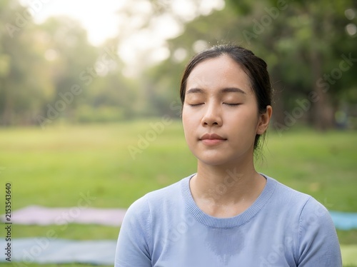 Asian woman meditating with eyes closed outdoor park yoga practice peaceful morning mind body wellness