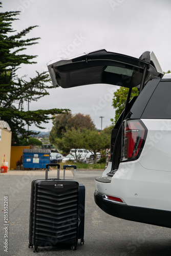 Travel-ready scene featuring packed suitcases positioned beside a premium SUV with its boot open, ready for loading. The image represents holiday preparation, road travel, family vacation