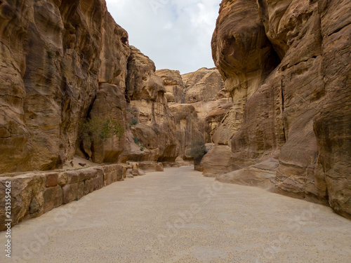 Bild auf Leinwand Sunlight illuminating the towering rose-red sandstone cliffs of The Siq, the nar