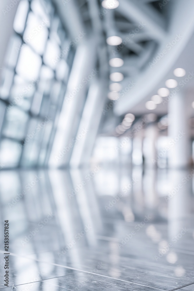 Fototapeta premium Abstract blurred interior view of a modern architectural space with large windows and polished floor reflections