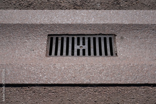 Canvas Print Cast iron water drainage grate in a stone gutter