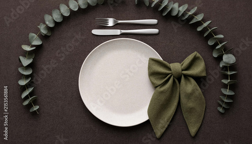 Elegant table setting with plate, cutlery, and eucalyptus on dark cloth