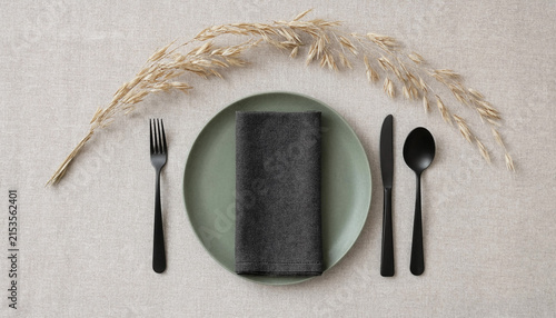 Minimalist table setting with green plate, dark napkin and black cutlery