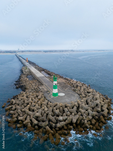 Фотография Green and white lighthouse on breakwater protecting harbor entrance