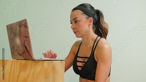 Mexican woman in her forties, athletic, using a laptop to join an online workout session at home