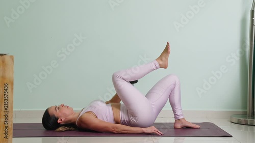 Mexican woman performing single leg glute bridges with a dumbbell for her online workout at home on a yoga mat