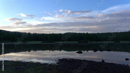 Time lapse of clouds reflecting on a calm lake in the morning light