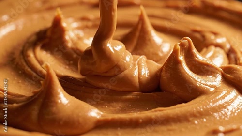 Thick swirling peanut butter with a glossy texture and rich brown color