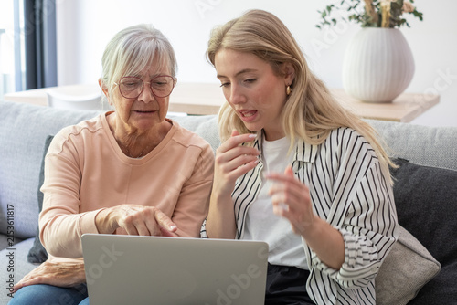 Cuadro en lienzo Granddaughter teaching grandmother how to use a laptop at home, bridging the gen