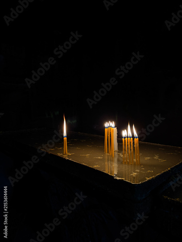 фотографія Burning candles in a church against a dark background, warm candlelight and spir