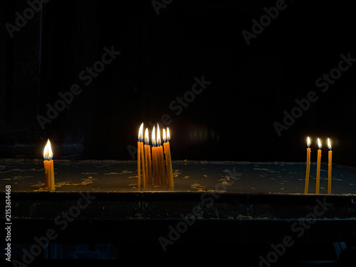 Obraz na plátně Burning candles in a church against a dark background, warm candlelight and spir