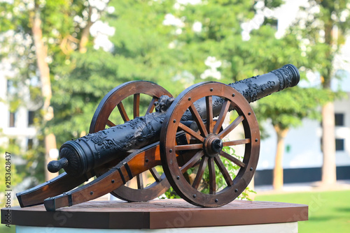 Quadro su tela Antique black metal cannon on wooden wheels displayed in a park setting