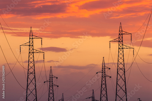 Tralicci elettrici al tramonto con cielo arancione