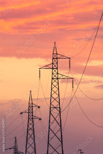 Tralicci elettrici al tramonto con cielo arancione