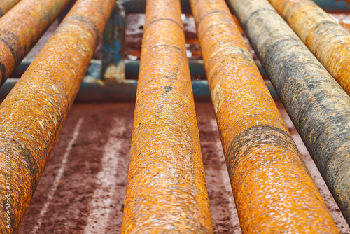 Fotografie Rows of old corroded iron tubing or weathered industrial pipeline materials at a construction scrap yard