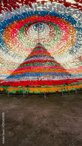 View of the Great Prayer Flag Area featuring a large conical structure covered in vibrant colorful prayer flags in Shangri-La, Yunnan, China.