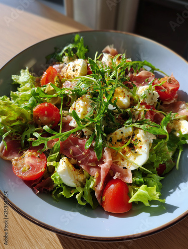 Salad with prosciutto, eggs, tomatoes, and arugula