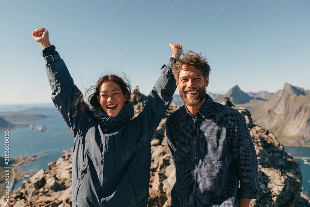 Fototapeta premium Joyful hiking couple on rugged mountain summit with fjord view celebrating outdoors for background and banner design