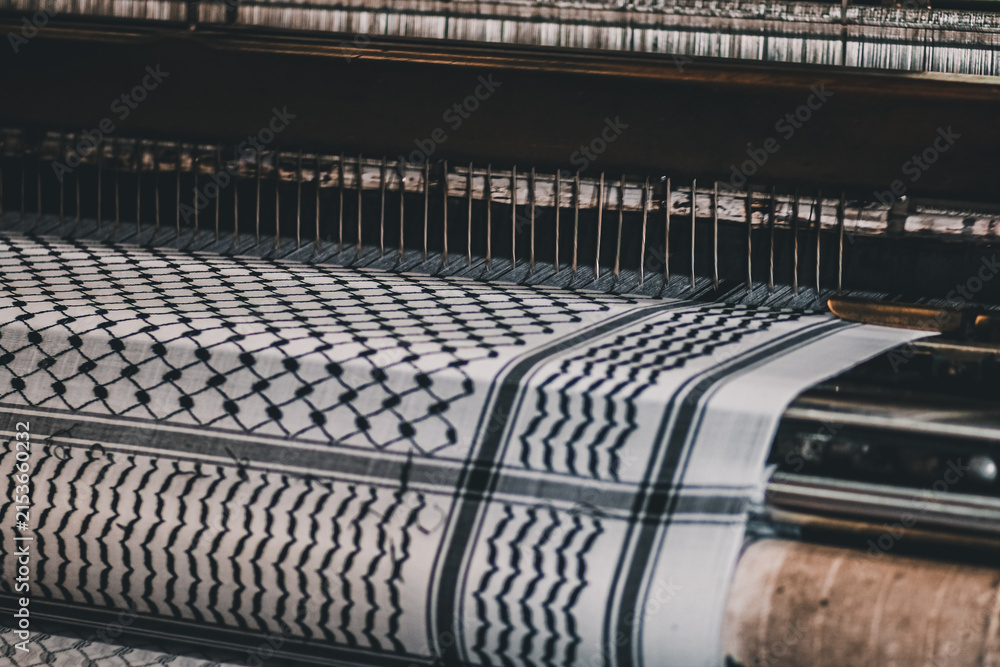 Fototapeta premium Traditional keffiyeh fabric moving through a weaving machine