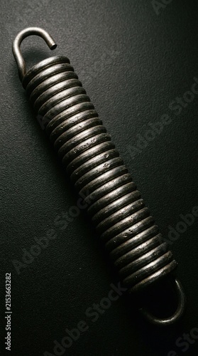 Metal spring rests on dark textured surface