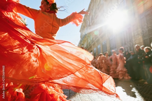 Flamenco dancer in a crimson ruffled skirt performing on a sunlit street for Spanish culture and travel festival features