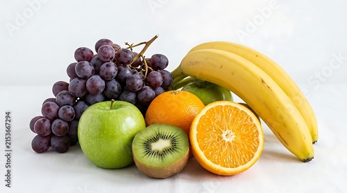 Fresh assorted fruits including grapes bananas apple kiwi and orange displayed together on clean surface
