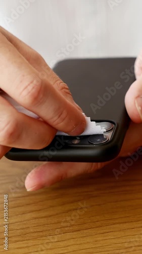 Close-up of person cleaning smartphone camera lenses with microfiber cloth for device care and maintenance