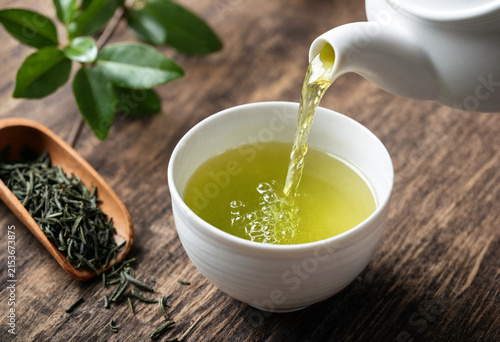 Pouring hot green tea into a white cup