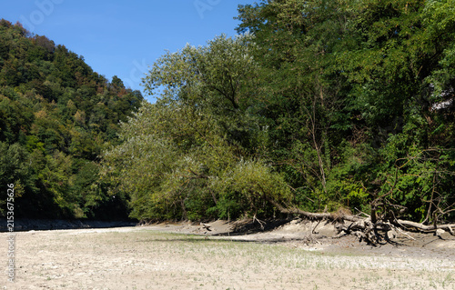Foto Dry and shallow riverbed with exposed rocks and stones during prolonged summer drought