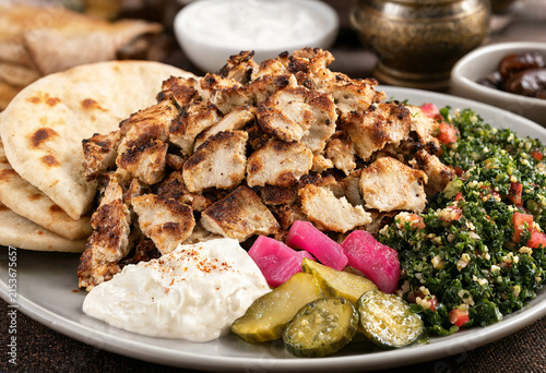 Delicious platter of sliced chicken shawarma served with warm pita bread, creamy garlic sauce, pickles, and fresh salad