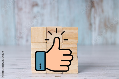 Thumbs-up symbol on a wooden block representing approval, positive feedback, and success; icon on wooden cubes. Realistic.