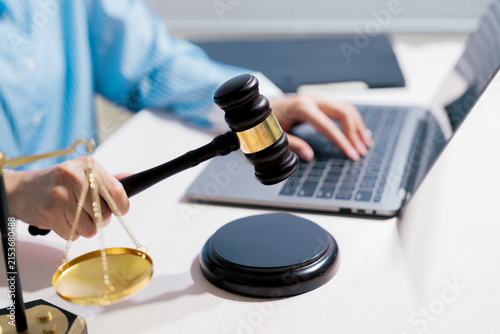 Digital law concept. Professional holding gavel while using laptop represents legal decision, online justice, court process, compliance, regulation, technology