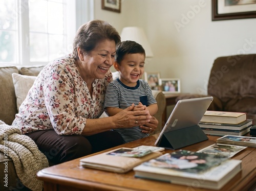 Elderly Hispanic Woman and Grandchild Setting Up Tablet for Video Call