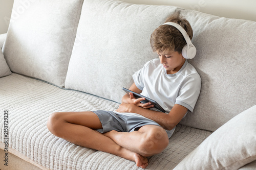 Foto Boy relaxing on a sofa while engaging in online learning, using a digital tablet