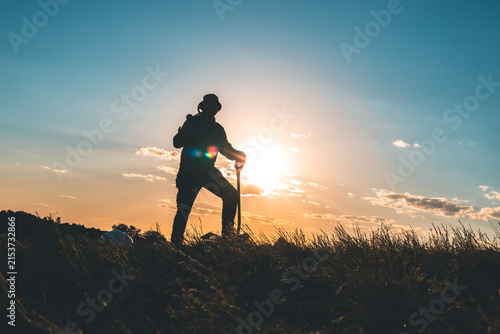 Morning Detectorist with Shovel in the Ground and Metal Detector on His Shoulder