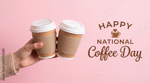Hand holding two takeaway coffee cups for National Coffee Day celebration