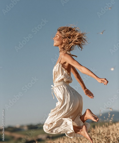 Young Woman Jumping Barefoot in a Flowing White Dress