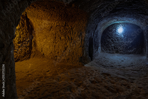 Canvastavla Rock-carved chambers and passageways inside an ancient underground city in Cappadocia, Turkey, illuminated with contrasting orange and blue lights