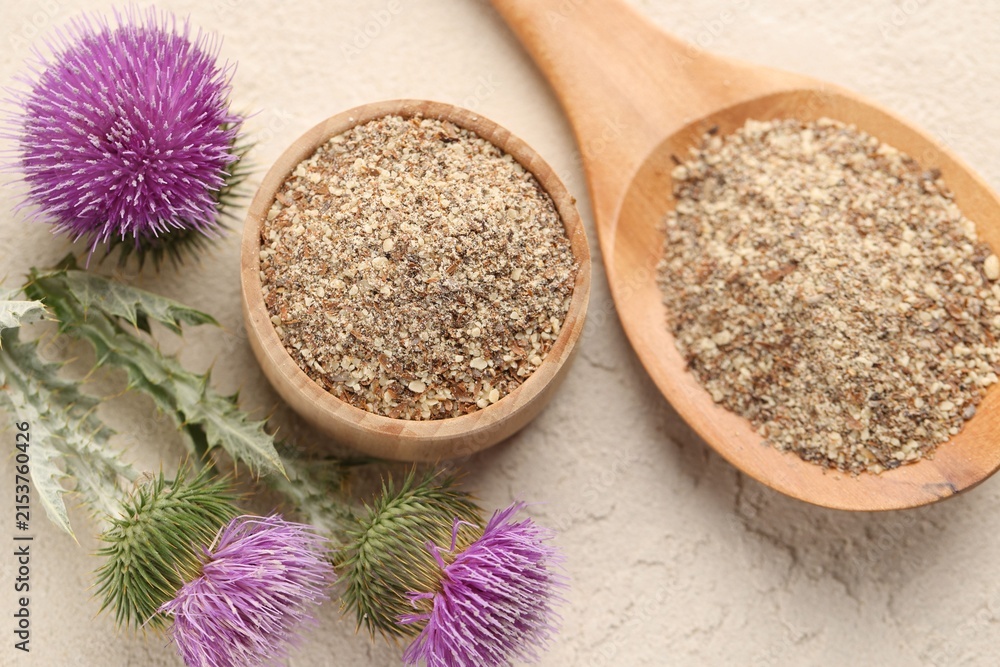 Fototapeta premium Ground milk thistle seeds and flowers on light table, flat lay