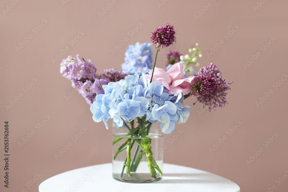 Obraz premium Bouquet of beautiful flowers in vase on white table near beige wall indoors, closeup