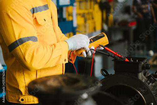Professional conceptual engineering in industrial plants. Focused technician feeling diligent while testing equipment with multimeter