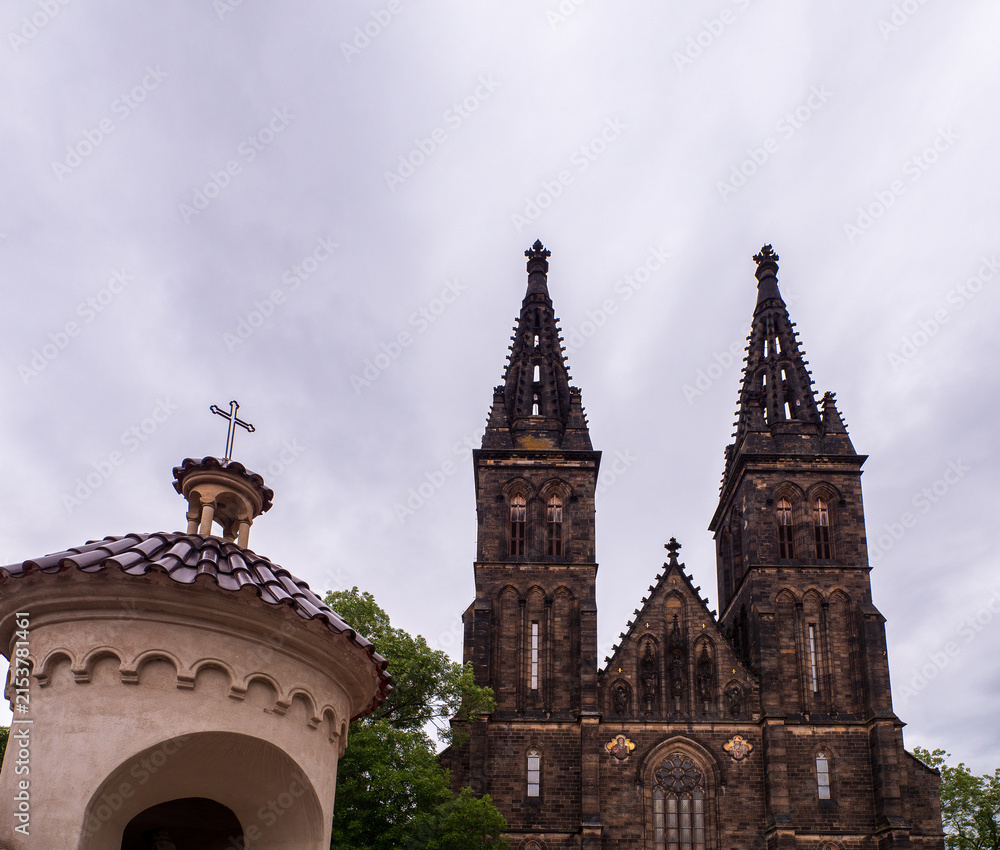 Fototapeta premium Romanesque Rotunda of St Martin and Neo-Gothic Basilica of St Peter and Paul at Vysehrad in Prague, Czech Republic, under an overcast sky.