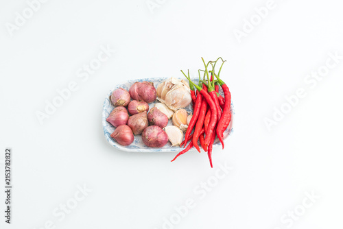 Obraz na plátně Fresh red chilies shallots and garlic on ceramic plate isolated on white backgro