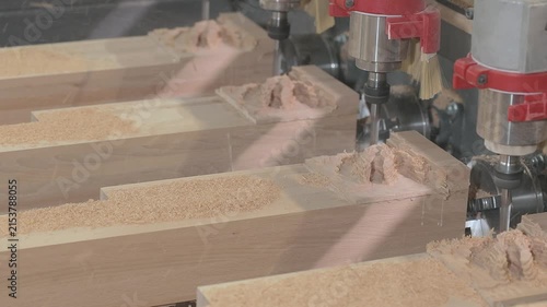 Close-up of a multi-spindle CNC router machine milling intricate carved decorative patterns into wooden workpieces in a furniture manufacturing workshop.