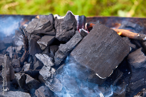 Foto Natural hardwood charcoal briquettes with smoke outdoors