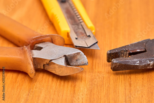 Photography Close-up of hand tools on wooden surface including pliers and utility knife
