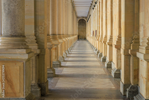 Obraz na płótnie Grand architectural pillars in symmetrical stone corridor with sunlight