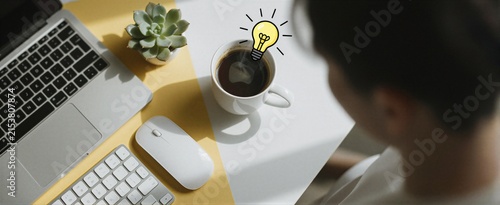 A top-down view of a workspace featuring a laptop, mouse, coffee, and succulent, bathed in warm sunlight, symbolizing inspiration and productivity.